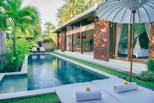 an outdoor pool with two loungers next to a house at Ruby Romance Oceanside Villas in Tejakula