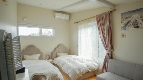 1 dormitorio con 2 camas y ventana en Joy House en Imari