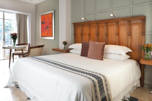 a bedroom with a large white bed with a wooden headboard at Real de Hamburgo By The Local Way in Mexico City
