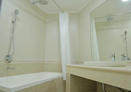 a bathroom with a tub and a sink and a mirror at Grand Ark Bukhara in Bukhara