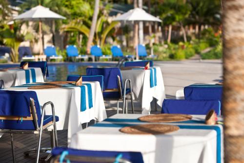 a row of tables and chairs with blue chairs at Coco de Mer Hotel and Black Parrot Suites in Grand'Anse Praslin