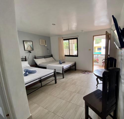 ein Wohnzimmer mit 2 Betten und einem Tisch in der Unterkunft Marion Roos Hotel in Puerto Galera
