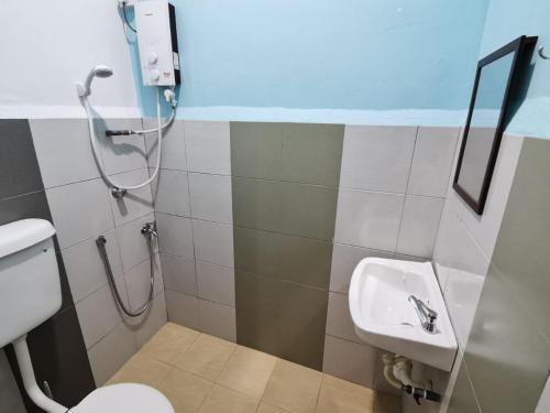 a bathroom with a shower and a toilet and a sink at SingLeisure Holiday House in Mersing