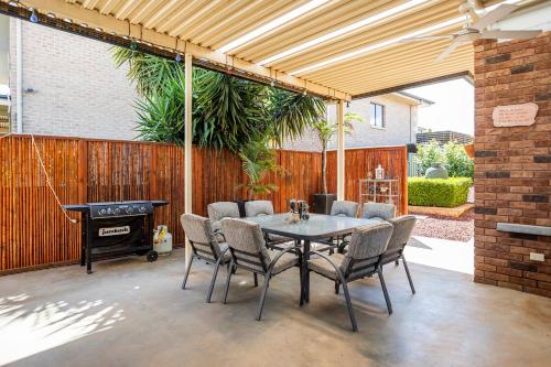 eine Terrasse mit einem Tisch, Stühlen und einem Grill in der Unterkunft Contractor's Heaven and Entertainer in Parkes