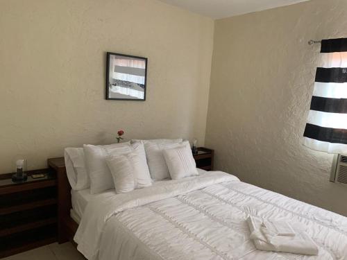 een slaapkamer met een bed met witte lakens en kussens bij Cozy Private Room, near the Airport - Free parking - 01 in Miami