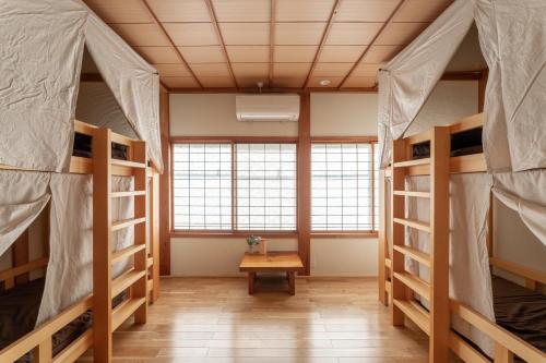 a room with three bunk beds and a table at Guest House Takazuri-KITA in Nanto