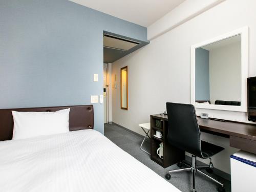 a bedroom with a bed and a desk and a computer at Hotel Wing International Miyakonojo in Miyakonozyō