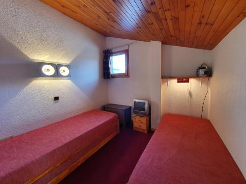 ラ・プラーニュにあるAppartement La Plagne, 3 pièces, 6 personnes - FR-1-353-5のベッド2台とテレビが備わる小さな客室です。