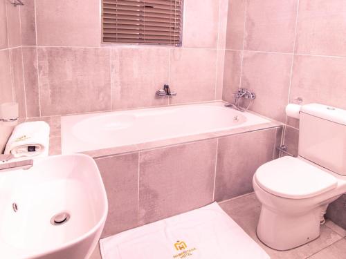 uma casa de banho com uma banheira, um WC e um lavatório. em Masingitana Hotel em Acornhoek