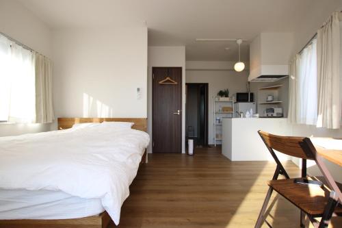 a bedroom with a large white bed and a kitchen at Kamatas STAY 京急蒲田駅 徒歩5分 in Tokyo