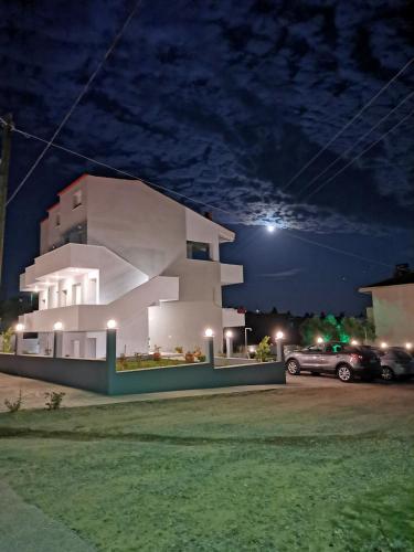 a white house with a parking lot at night at The House Of The Roses in Yerakiní