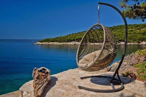 a swing sitting on a rock near the water at Luxury Beachfront Villa Palazzo di Mare with private heated pool and staff at the beach on Brac island - Sumartin in Selca