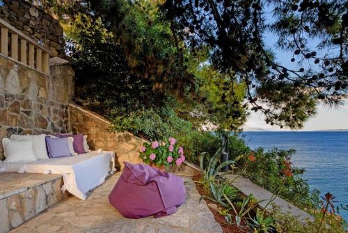 a couch sitting on a stone wall next to the water at Luxury Beachfront Villa Palazzo di Mare with private heated pool and staff at the beach on Brac island - Sumartin in Selca