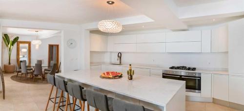 a kitchen with white cabinets and a island with chairs at Luxury Beachfront Villa Palazzo di Mare with private heated pool and staff at the beach on Brac island - Sumartin in Selca