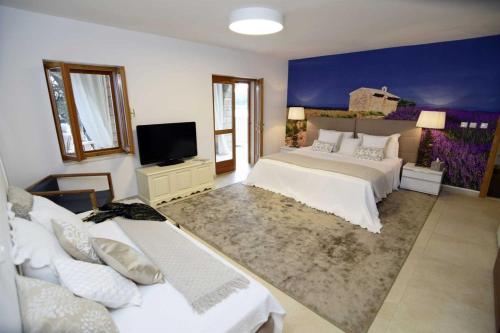 a large bedroom with two beds and a tv at Luxury Beachfront Villa Palazzo di Mare with private heated pool and staff at the beach on Brac island - Sumartin in Selca