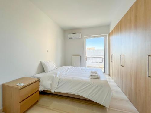 a white bedroom with a bed and a window at Panoramic Cityscape Maisonette in Agios Dimitrios in Athens
