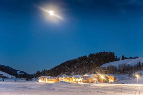 a house in the snow at night with the moon at Pradas Resort Brigels in Brigels