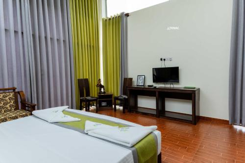 a room with two beds and a desk with a television at Nelinsa Resort and Spa in Matale