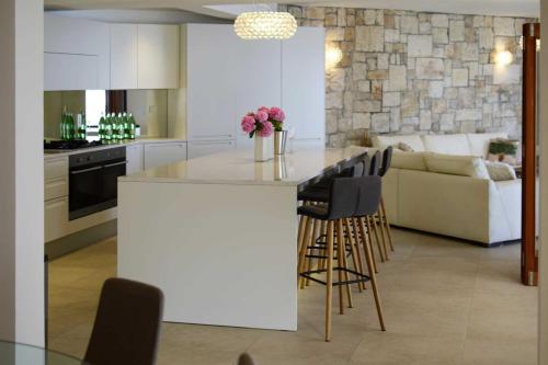 a kitchen and living room with a counter and chairs at Luxury Beachfront Villa Palazzo di Mare with private heated pool and staff at the beach on Brac island - Sumartin in Selca