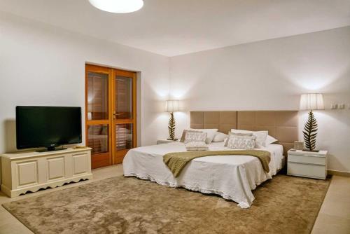 a bedroom with a large bed and a flat screen tv at Luxury Beachfront Villa Palazzo di Mare with private heated pool and staff at the beach on Brac island - Sumartin in Selca