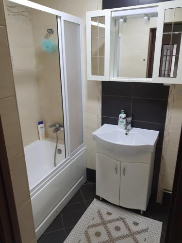 a bathroom with a white sink and a shower at Апартаменты в тихом месте in Chişinău