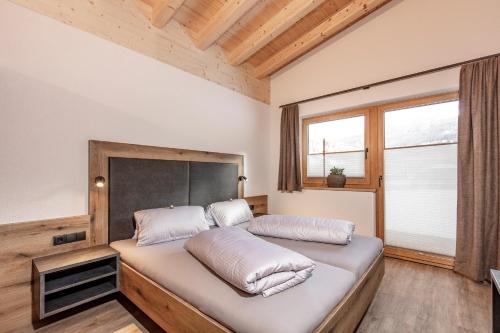 a bedroom with a large bed with a large window at Landhaus Sonnenwiese in Sölden