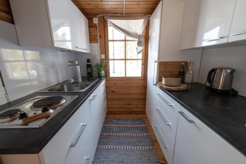 a kitchen with white cabinets and a sink and a window at Metsä Kolo in Saariharju