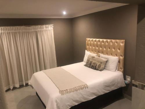 een slaapkamer met een groot bed met witte lakens en kussens bij Charli’s Lodge in Mpheleng