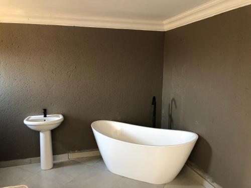 a bathroom with a white bath tub next to a sink at Charli’s Lodge in Mpheleng