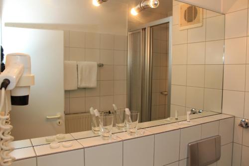 a bathroom with a large mirror and a sink at Hotel Rüttenscheider Stern in Essen