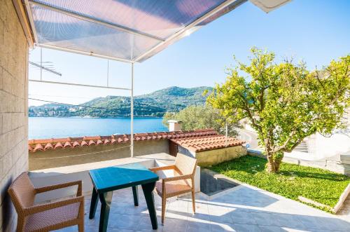 a patio with a table and chairs and a view of the water at Apartments Violić in Zaton