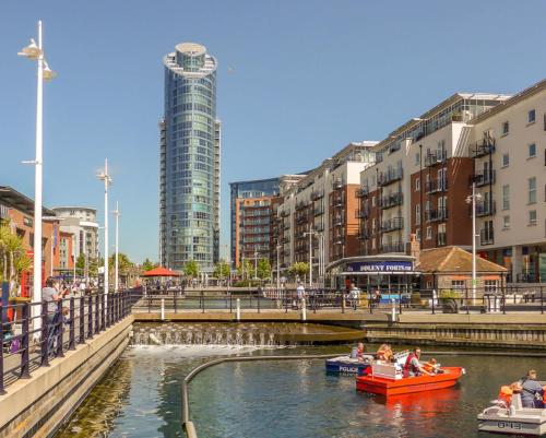 a group of people in boats in a river with buildings at GWQ Apartments Luxe in Portsmouth