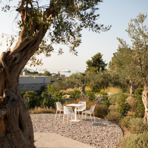 a table and chairs in a garden with a tree at Elies Residences Luxury Apartments in Mytilini