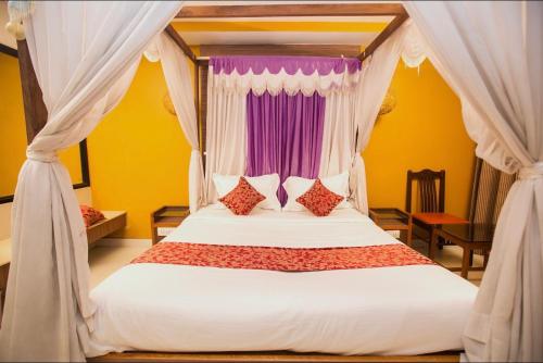 a bedroom with a canopy bed with red and purple pillows at Hotel Maneck Residency in Ooty