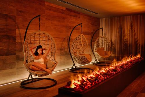 a woman sitting in a wicker chair next to a fireplace at Grand Hotel Victoria concept & spa, by R Collection Hotels in Menaggio