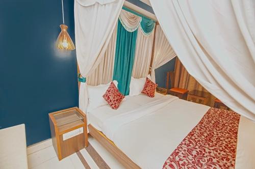 a bedroom with a white bed with red pillows at Hotel Maneck Residency in Ooty