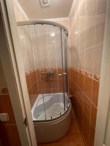 een douche in een betegelde badkamer met een bad bij Seven Hotel in Korosten