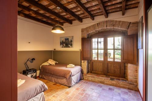 a bedroom with two beds and a wooden door at Ca la Masovera - Mas Vinyoles Natura in Sant Pere de Torelló