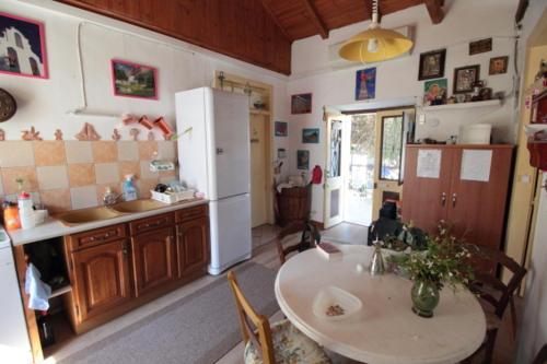 a kitchen with a table and a white refrigerator at Au pied de la falaise rouge in Leonidion