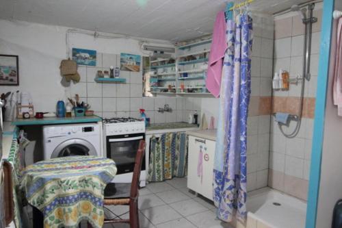 a small kitchen with a stove and a washing machine at Au pied de la falaise rouge in Leonidion