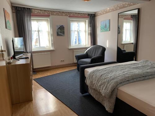 ein Schlafzimmer mit einem Bett, 2 Stühlen und einem TV in der Unterkunft Ferienhaus zwischen Bach und Luther mit Sauna & Garten in Eisenach
