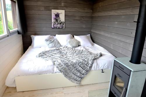 1 dormitorio con cama con edredón y almohadas blancos en Cabane dans les arbres / Swin-golf de Cremin, en Cremin