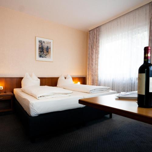a hotel room with two beds and a bottle of wine at Hotel Wegener in Mannheim