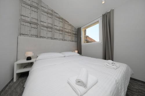 a bedroom with a white bed and a window at Downtown Boutique Hostel in Zadar