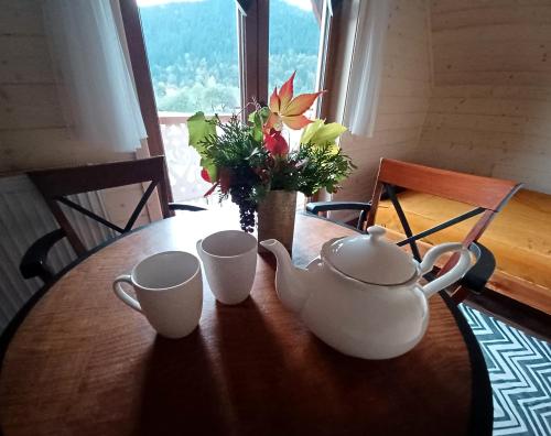 a table with two tea cups and a vase with flowers at Gazdówka - najlepsza miejscówka domek w Pieninach in Krościenko