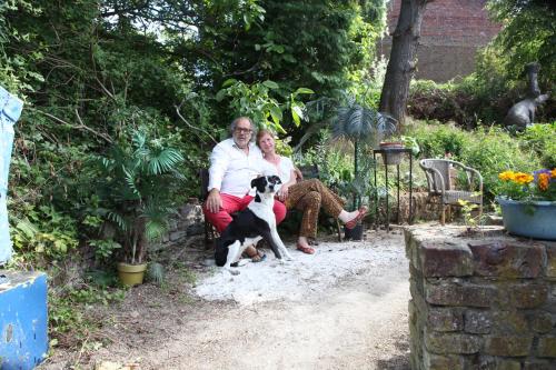 a man and woman sitting on a bench with a dog at B&B De Henehoeve in Heks