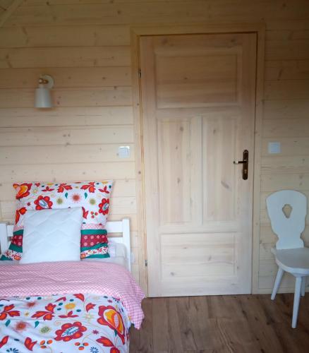 a bedroom with a bed and a chair and a door at Gazdówka - najlepsza miejscówka domek w Pieninach in Krościenko