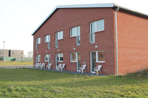 a group of white chairs sitting outside of a brick building at Hotel Birten in Xanten