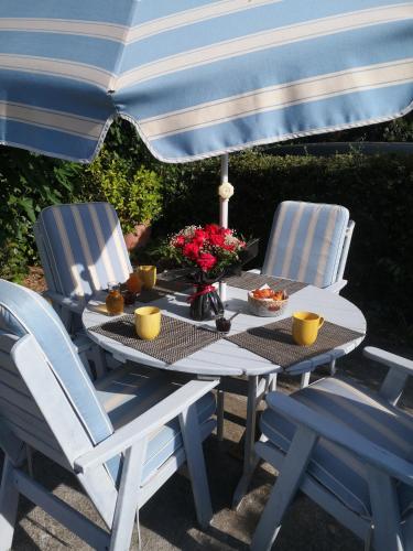 a table with two chairs and an umbrella at Chambres d'Hôtes Le Mas du Bijou Bleu in Puget-sur Argens