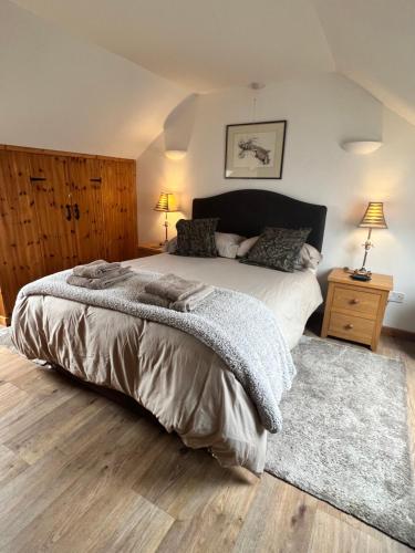 a bedroom with a large bed and a rug at Beudy Bach in Cross Hands